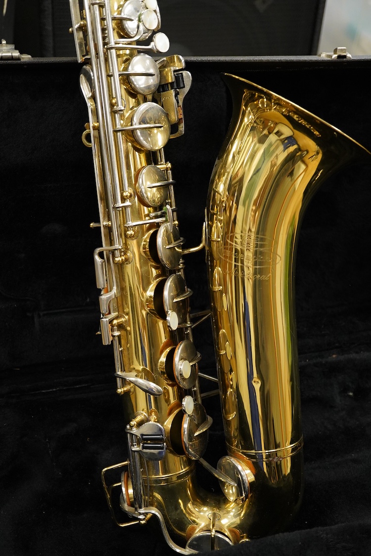 A cased Buescher Aristocrat tenor saxophone and stand